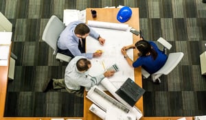 A group of people sat around a desk looking at building plans